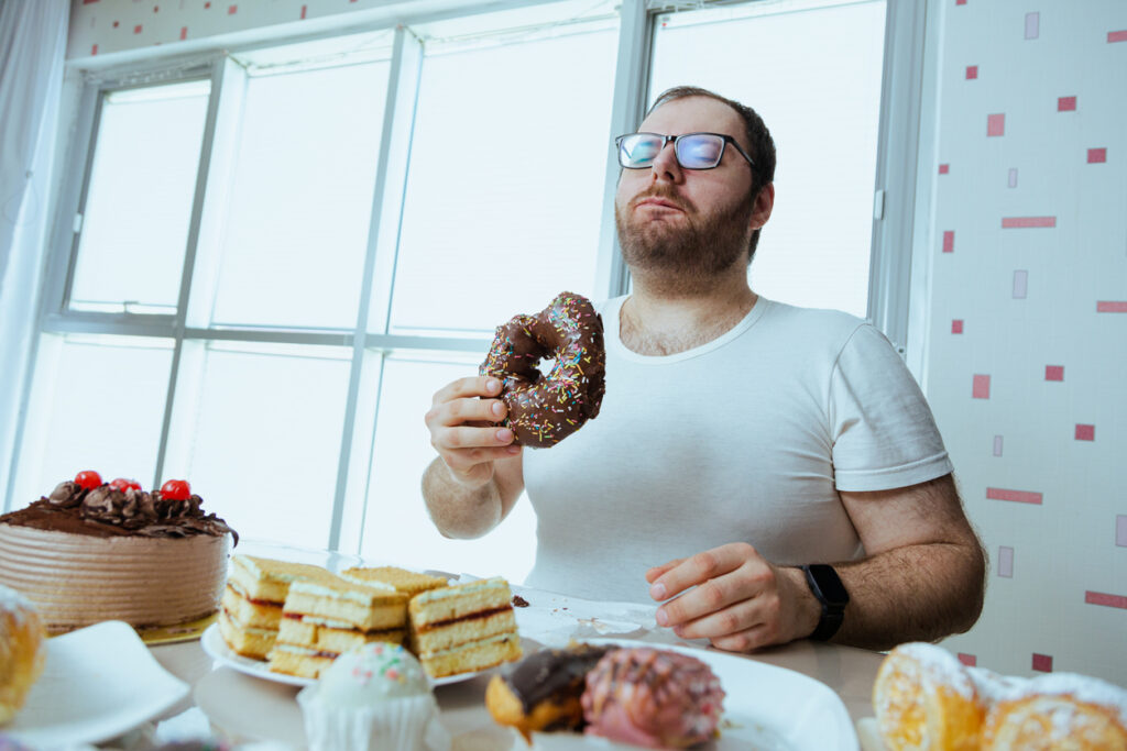 Health problems and extra weight problems because of eating fatty food, fat man with donuts.